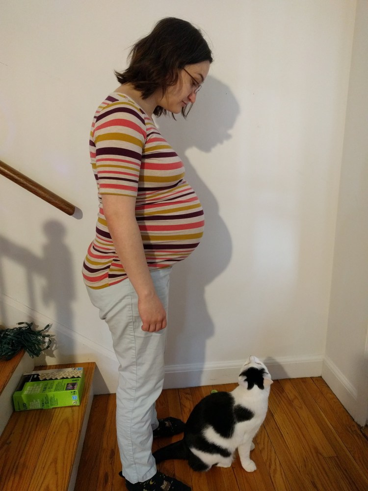 I am standing, showing my profile, looking down at my cat, who is looking up at me.