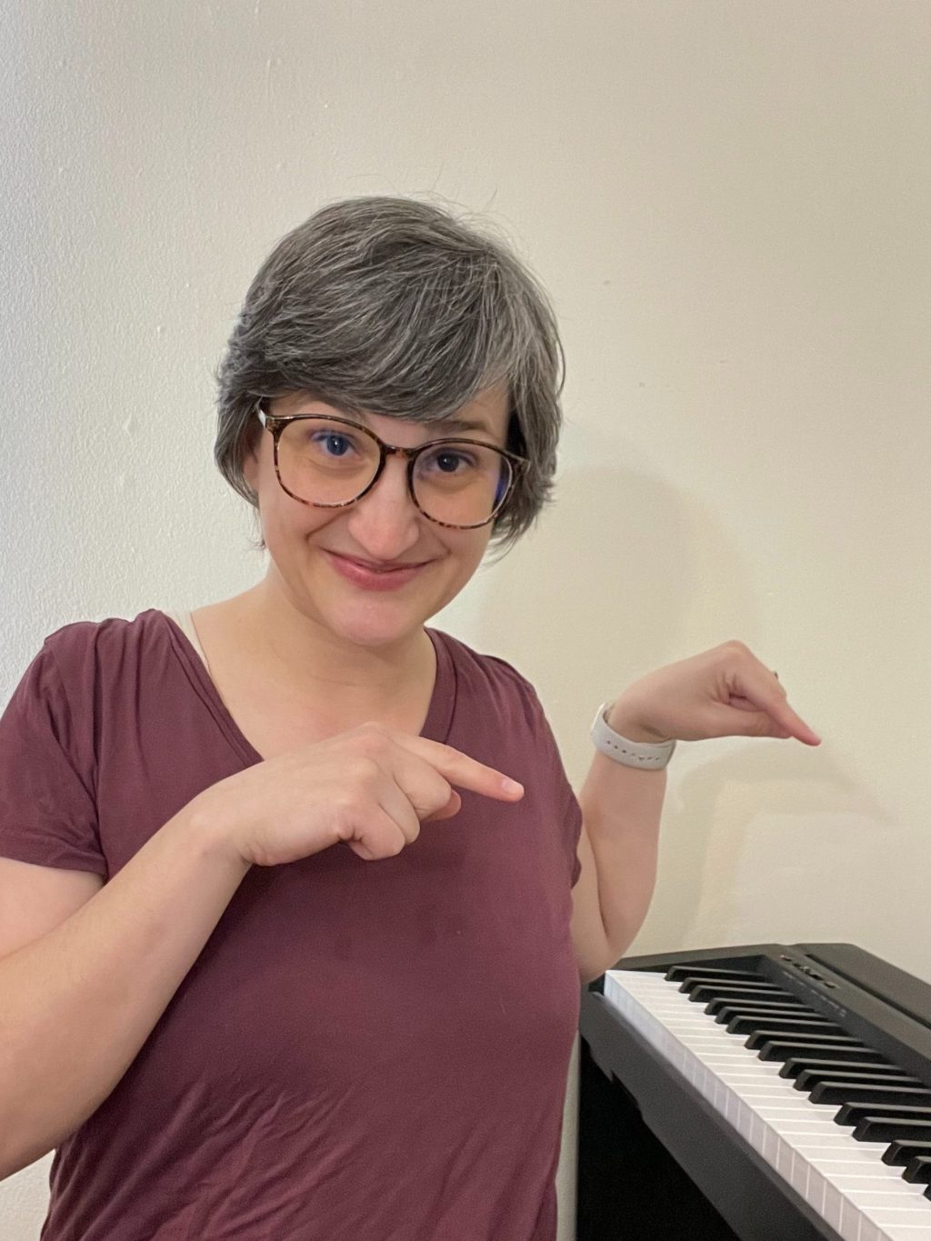The author smiles and points down at her digital piano.